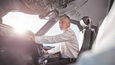 Two pilots are running towards an aircraft on the runway