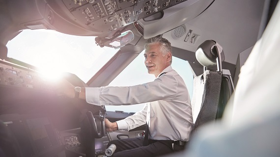 Ein Pilot sitzt lächelnd in einem Cockpit 