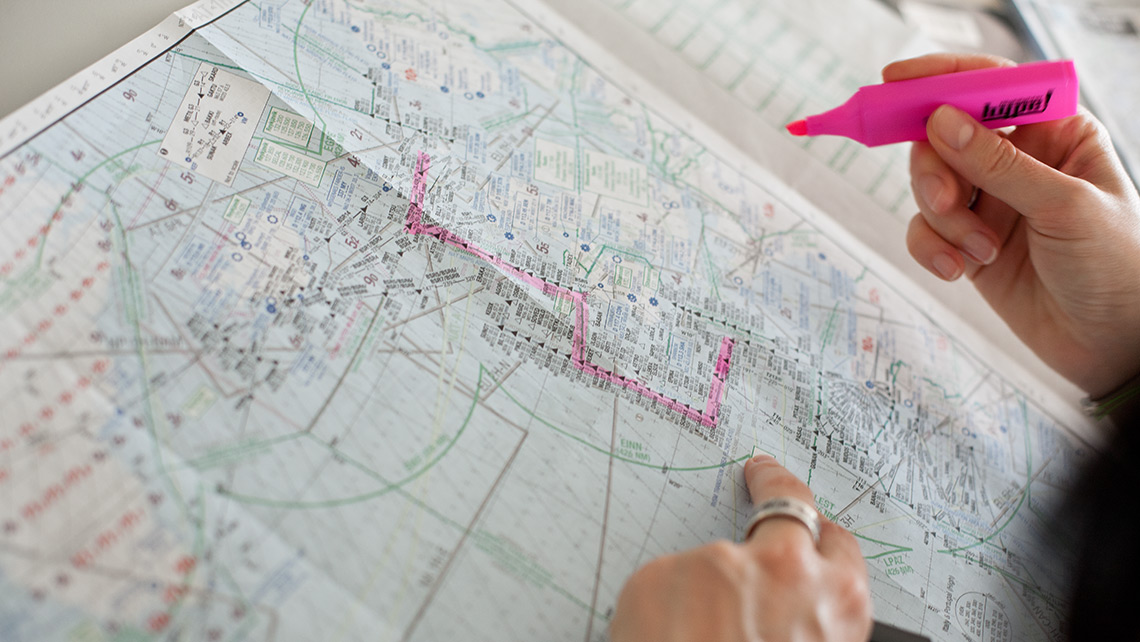 A dispatcher marks something with a red highlighter on a flight map