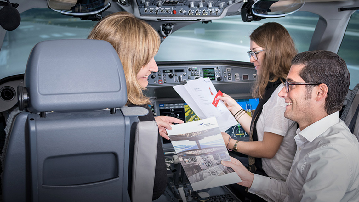 zwei lächelnde Frauen und ein lächelnder Mann sitzen in einem Cockpit