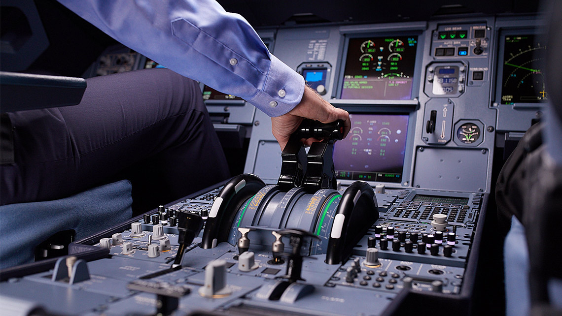 Ein Mann bedient die Schubkontrolle in einem Flugzeugcockpit