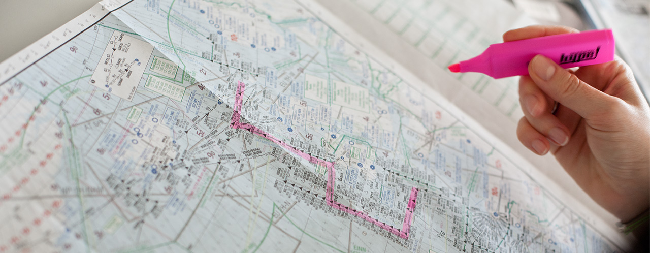 A dispatcher marks something with a red highlighter on a flight map