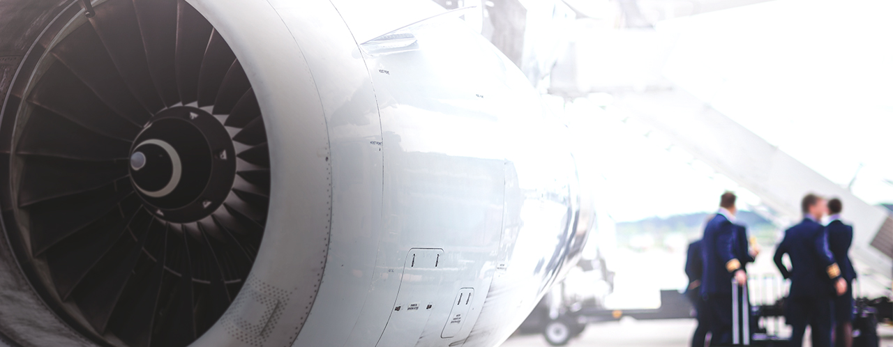 Aircraft turbine in the foreground, an aircraft crew next to the gangway in the background