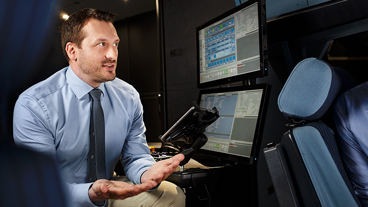 An instructor explains something to a training participant in an aircraft simulator