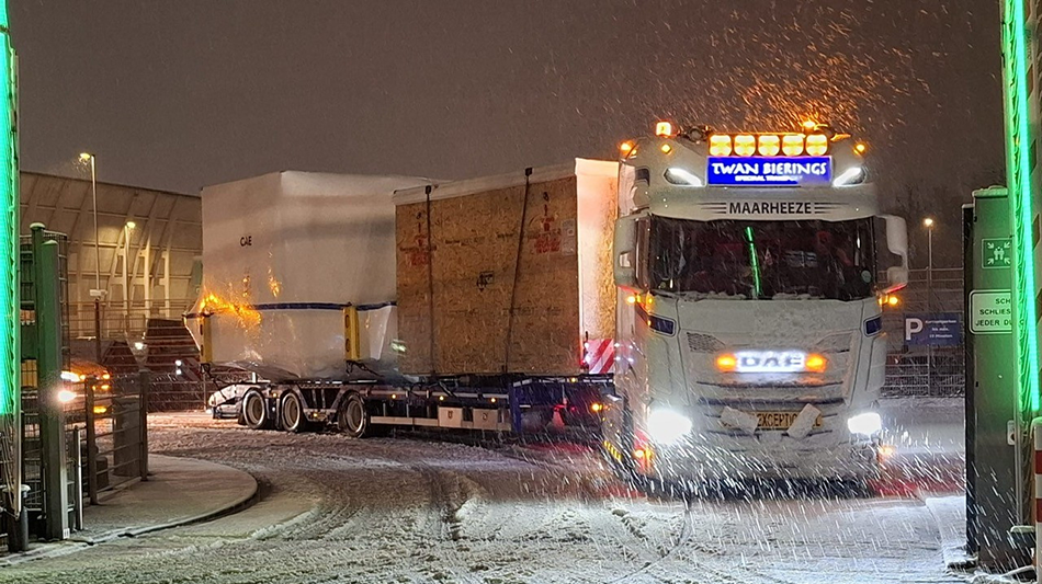 A truck loaded with a simulator drives through the snow.