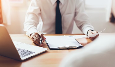 A person is sitting at a desk with a laptop and documents.