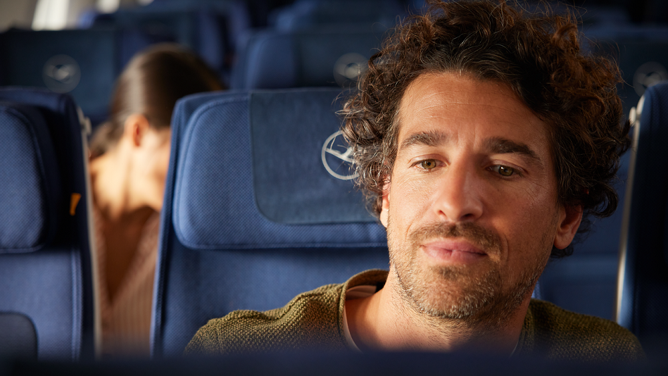 Eine Person mit kurzen, lockigen Haaren sitzt in einem Flugzeug.