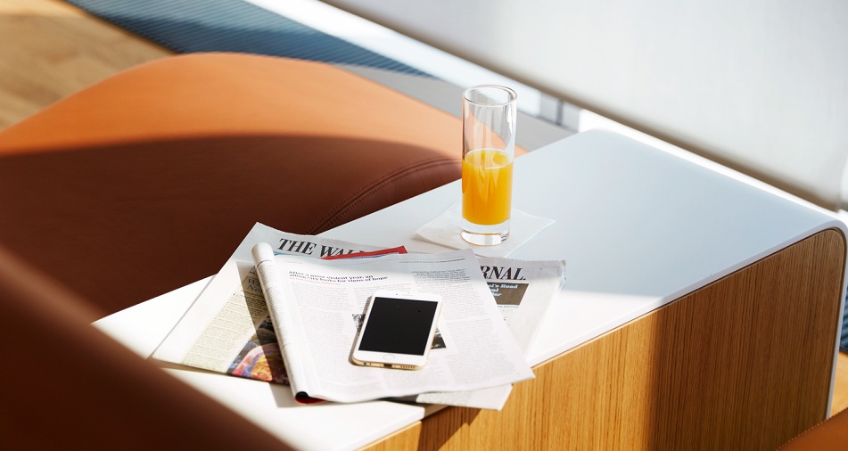 Auf einem Tisch liegen Zeitungen und ein Smartphone.