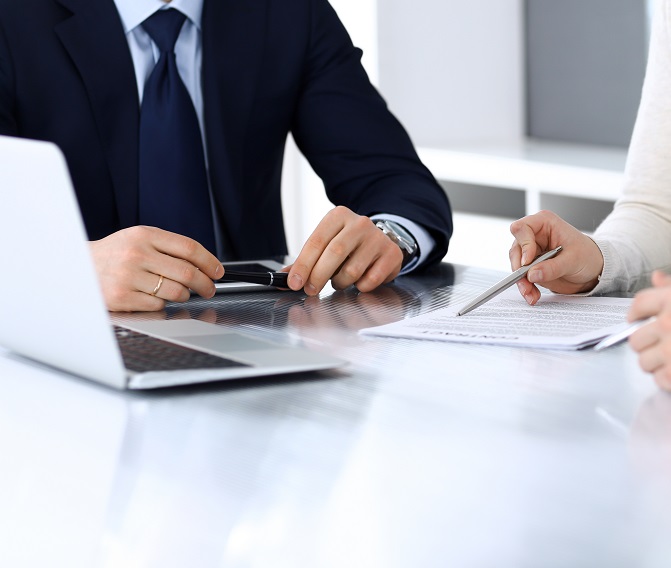 Two people are sitting at a table with a laptop.